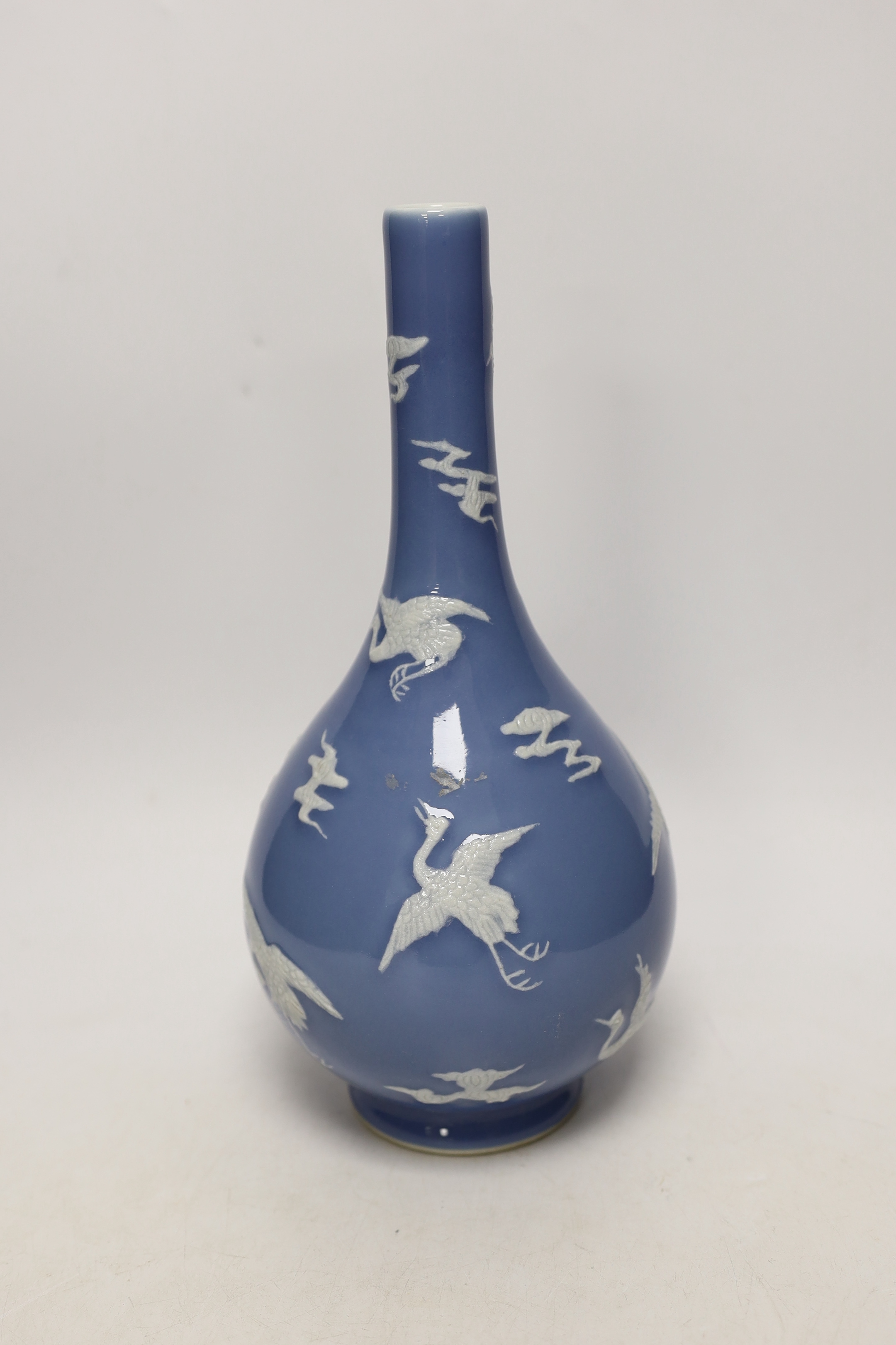 A Chinese blue bottle vase decorated in relief with cranes, on stand, 32cm high overall